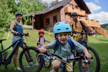 A young family with little children preaparing for bike ride, in front of house. - HPIF01966