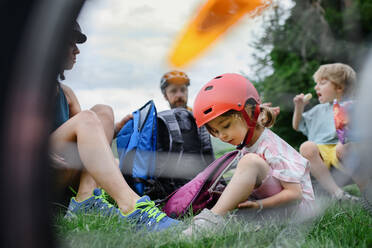 Eine junge Familie mit kleinen Kindern ruht sich nach einer Radtour im Sommer im Gras eines Parks aus. - HPIF01983