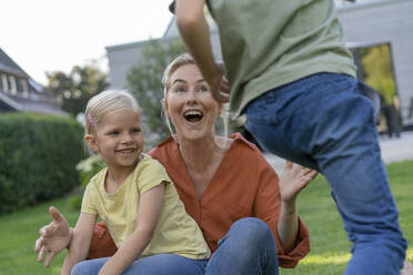 Happy mother enjoying with son and daughter in back yard - JOSEF15019