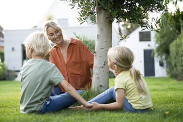 Happy mother holding children's hands in back yard - JOSEF15024