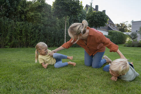 Verspielte Mutter spielt mit Kindern im Garten - JOSEF15055