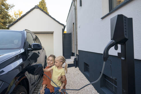 Mutter leitet Tochter an, Elektroauto im Vorgarten aufzuladen - JOSEF15100