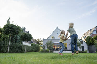 Happy girl holding brother's hand playing in back yard - JOSEF15128