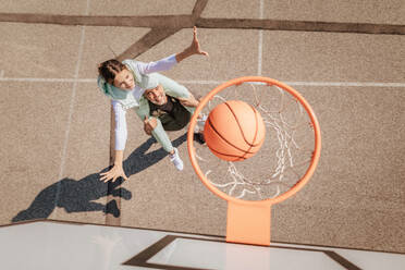 Vater und Tochter im Teenageralter spielen draußen auf dem Platz Basketball, Blick von oben auf das Netz des Basketballkorbs. - HPIF02024