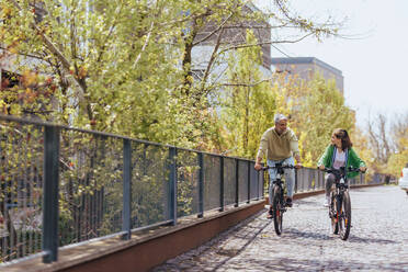 A happy father with teenage daughter on cycle ride in town. - HPIF02043