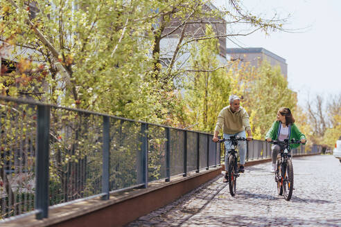 Ein glücklicher Vater mit seiner Tochter im Teenageralter auf einer Radtour in der Stadt. - HPIF02043