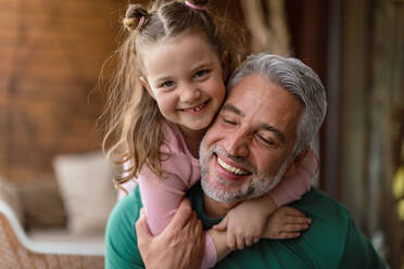 Ein Porträt der kleinen süßen Tochter, die ihren glücklichen Vater zu Hause umarmt. - HPIF02062