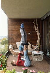 Two little sisters doing acrobatic exercise together at home on a balcony. - HPIF02068