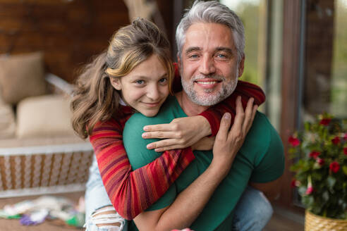 Ein Porträt der Teenager-Tochter, die ihren glücklichen Vater zu Hause umarmt. - HPIF02069