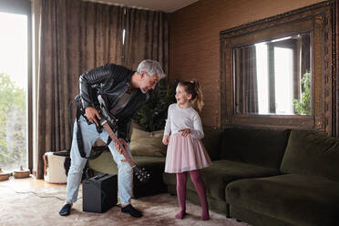 Ein Vater, der Rockgitarrist ist, hat Spaß und tanzt mit seiner kleinen Tochter zu Hause. - HPIF02084