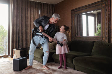 Ein Vater, der Rockgitarrist ist, hat Spaß und tanzt mit seiner kleinen Tochter zu Hause. - HPIF02085
