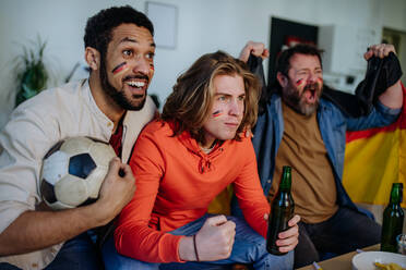 Happy German football fans friends watching football at home and celebrating success - HPIF02087