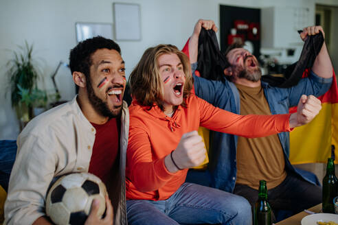 Glückliche deutsche Fußballfans, die zu Hause Fußball schauen und den Erfolg feiern - HPIF02089