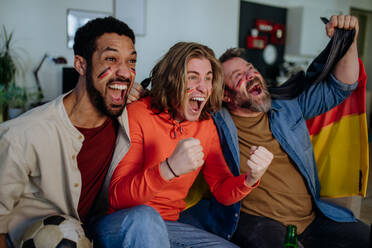 Happy German football fans friends watching a football at home and celebrating. - HPIF02090