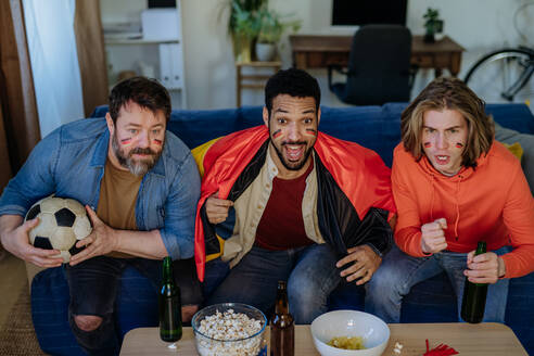 Nervöse Freunde von Fußballfans starren auf den Fernseher und sehen sich zu Hause ein Fußballspiel an. - HPIF02112