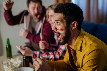 A close-up of excited football fan watching match with friends at home. - HPIF02126