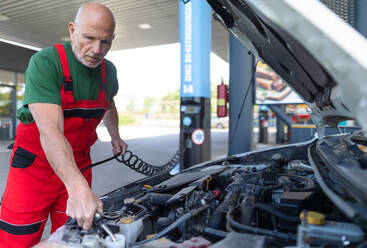 Ein erfahrener Mechaniker prüft den Ölstand im Motor eines Autos. - HPIF02164