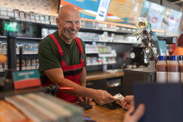 Ein Angestellter nimmt an einer Tankstelle Bargeld von einem Kunden entgegen, Nahaufnahme - HPIF02167