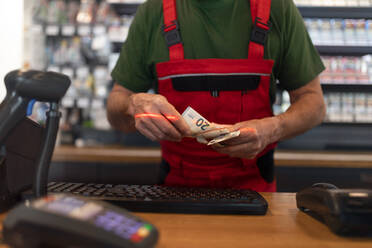 Ein Angestellter nimmt an einer Tankstelle Bargeld von einem Kunden entgegen, Nahaufnahme - HPIF02168