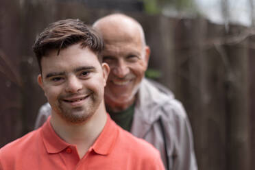 A portrait of happy senior father with his young son with Down syndrome outdoors. - HPIF02205