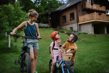 Eine junge Familie mit kleinen Kindern bereitet sich auf eine Fahrradtour vor dem Haus vor. - HPIF02209