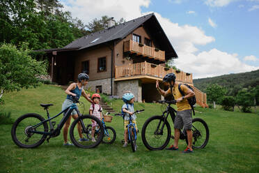 Eine junge Familie mit kleinen Kindern bereitet sich auf eine Fahrradtour vor dem Haus vor. - HPIF02211