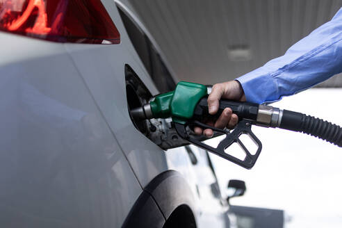 Eine Hand, die das Auto an der Tankstelle mit Kraftstoff betankt - HPIF02230