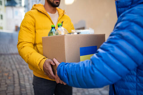 Ein Bildausschnitt von Freiwilligen, die eine Kiste mit humanitärer Hilfe für ukrainische Flüchtlinge auf der Straße sammeln - HPIF02242
