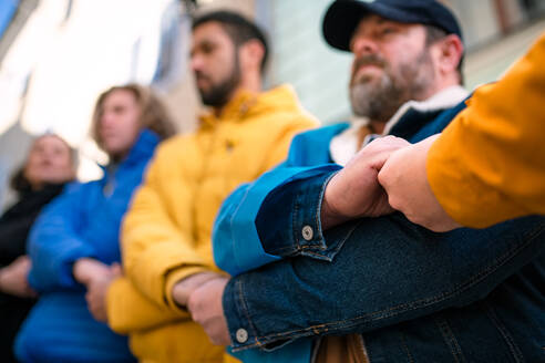 A cropped shot of protestors with in Ukrainian colors protesting against war in Ukraine in street - HPIF02256