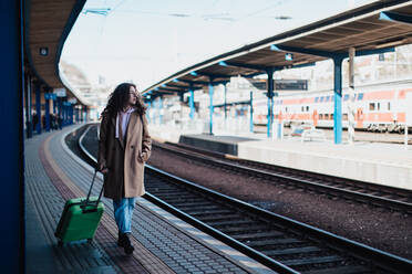 Eine glückliche junge Reisende Frau mit Gepäck wartet auf Zug am Bahnhof Plattform - HPIF02259