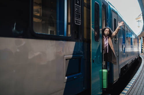 Eine glückliche junge Reisende Frau mit Gepäck beim Aussteigen aus dem Zug am Bahnhof Plattform - HPIF02261