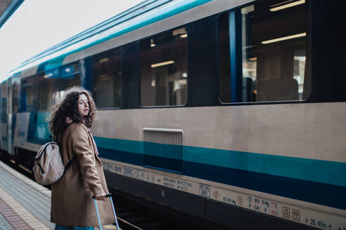 Eine glückliche junge Reisende Frau mit Gepäck wartet auf Zug am Bahnhof Plattform - HPIF02262