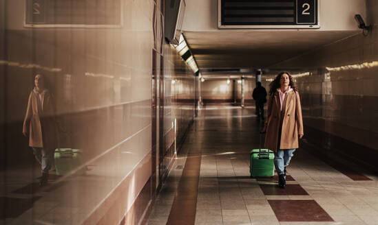 Eine Frau, die mit ihrem Gepäck durch den Bahnhof reist. - HPIF02266