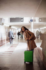 A woman traveler tourist with luggage standing in station and waiting somebody. - HPIF02267