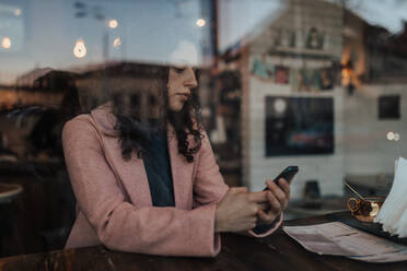 Eine junge Frau trinkt Tee und schreibt eine SMS, während sie ihre Freizeit allein in einem Café genießt - HPIF02287