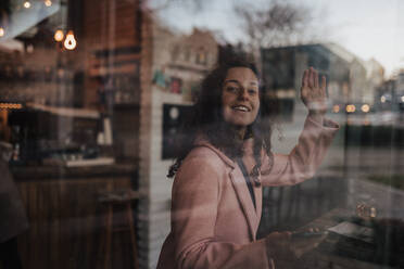 Eine junge Frau trinkt Tee und schaut aus dem Fenster eines Cafés, während sie ihre Freizeit alleine genießt - HPIF02288