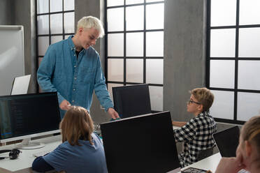 Schulkinder mit Hilfe eines Lehrers bei der Benutzung eines Computers im Klassenzimmer in der Schule - HPIF02311