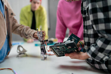 Kids with a teacher working together on project with electric toys and robots at robotics classroom, close-up - HPIF02334