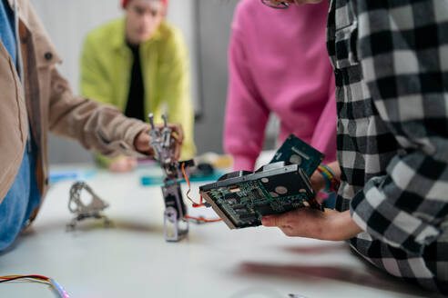 Kinder mit einem Lehrer arbeiten zusammen an einem Projekt mit elektrischen Spielzeugen und Robotern im Robotik-Klassenzimmer, Nahaufnahme - HPIF02334