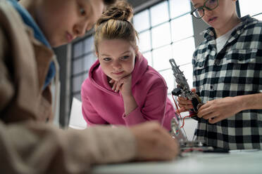 Eine Gruppe glücklicher Kinder mit ihrem Lehrer der Naturwissenschaften mit elektrischen Spielzeugen und Robotern im Robotik-Klassenzimmer, Nahaufnahme für Mädchen - HPIF02337