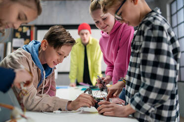 A group of happy kids with their science teacher with electric toys and robots at robotics classroom - HPIF02338