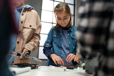 A group of happy kids with their science teacher with electric toys and robots at robotics classroom, close up for girl - HPIF02340