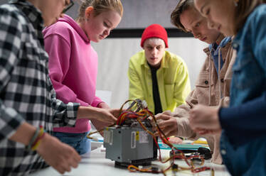 Eine Gruppe glücklicher Kinder mit ihrem Naturwissenschaftslehrer mit elektrischen Spielzeugen und Robotern im Robotik-Klassenzimmer - HPIF02344