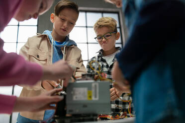 Kinder mit einem Lehrer arbeiten gemeinsam an einem Projekt mit elektrischen Spielzeugen und Robotern im Robotik-Klassenzimmer. - HPIF02346