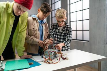 A group of happy kids with their science teacher with electric toys and robots at robotics classroom - HPIF02352