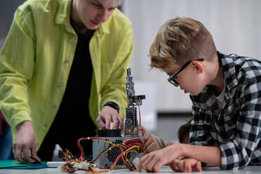 Student with teacher working together on project with electric toys and robots at robotics classroom - HPIF02353
