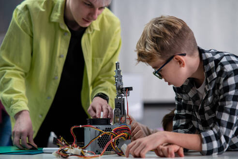 Schüler und Lehrer arbeiten gemeinsam an einem Projekt mit elektrischen Spielzeugen und Robotern im Robotik-Klassenzimmer - HPIF02353