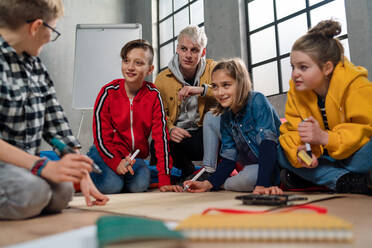 Eine Gruppe glücklicher Kinder mit ihrem Lehrer, die gemeinsam an einem Projekt im Klassenzimmer arbeiten. - HPIF02356