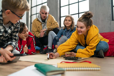 Eine Gruppe glücklicher Kinder mit ihrem Lehrer, die gemeinsam an einem Projekt im Klassenzimmer arbeiten. - HPIF02359