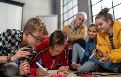Eine Gruppe glücklicher Kinder mit ihrem Lehrer, die gemeinsam an einem Projekt im Klassenzimmer arbeiten. - HPIF02360